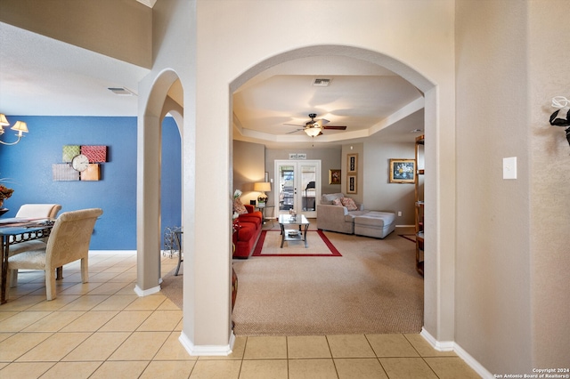 hallway with a raised ceiling, light carpet, french doors, and an inviting chandelier