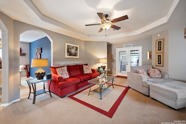 carpeted living room with ceiling fan, french doors, and a tray ceiling