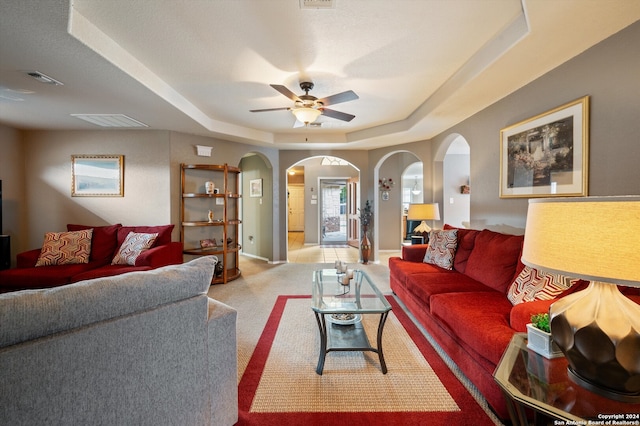 carpeted living room featuring a tray ceiling and ceiling fan