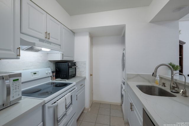 kitchen with light tile patterned floors, white cabinetry, white range with electric cooktop, and light stone counters