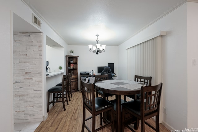 dining space with light hardwood / wood-style floors, an inviting chandelier, and ornamental molding