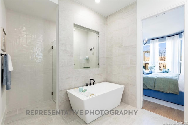 ensuite bathroom with tile walls, a soaking tub, ensuite bathroom, a stall shower, and tile patterned flooring