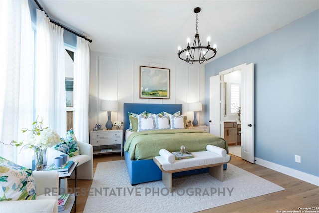 bedroom featuring baseboards, wood finished floors, connected bathroom, and a notable chandelier