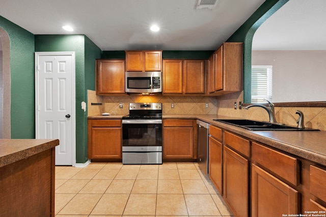 kitchen featuring backsplash, light tile patterned flooring, sink, and appliances with stainless steel finishes