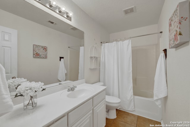 full bathroom featuring vanity, a textured ceiling, shower / bath combo with shower curtain, tile patterned flooring, and toilet