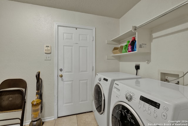 washroom featuring washer and dryer, light tile patterned floors, and a textured ceiling