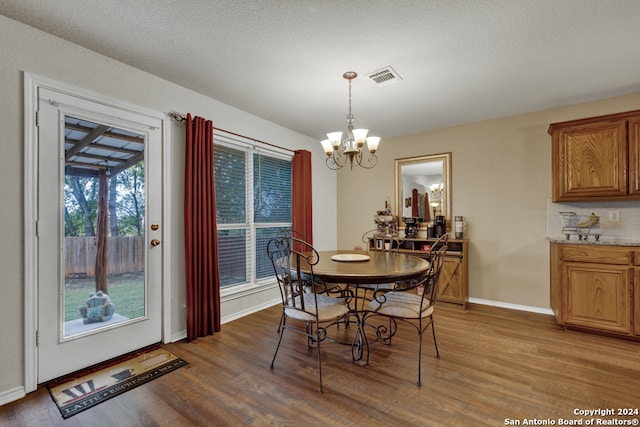 dining room featuring hardwood / wood-style floors, a textured ceiling, and an inviting chandelier