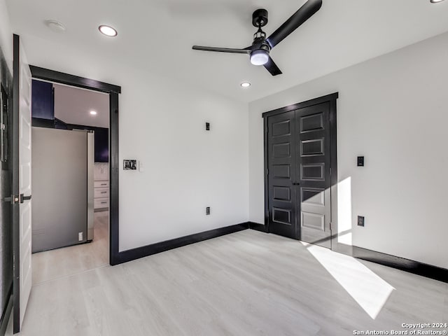 unfurnished bedroom with stainless steel refrigerator, ceiling fan, a closet, and light wood-type flooring