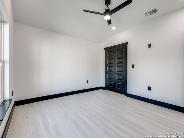 spare room featuring ceiling fan, light wood-type flooring, and lofted ceiling