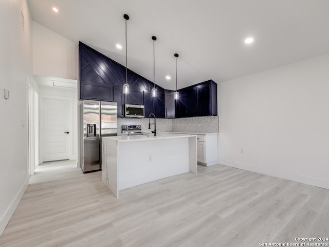 kitchen featuring pendant lighting, light wood-type flooring, stainless steel appliances, and a center island with sink