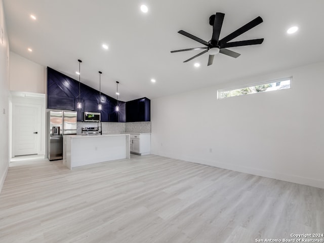 kitchen with appliances with stainless steel finishes, a kitchen island with sink, ceiling fan, pendant lighting, and light hardwood / wood-style flooring