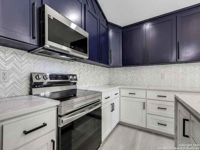 kitchen featuring white cabinets, stainless steel appliances, light stone counters, and light hardwood / wood-style floors