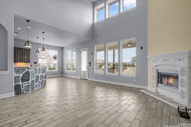 unfurnished living room with a towering ceiling and light hardwood / wood-style flooring