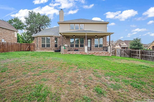 back of property with ceiling fan and a yard