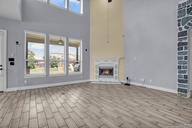 unfurnished living room featuring a towering ceiling, light hardwood / wood-style floors, and a wealth of natural light