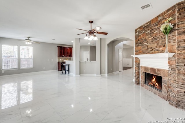 unfurnished living room with a fireplace and ceiling fan