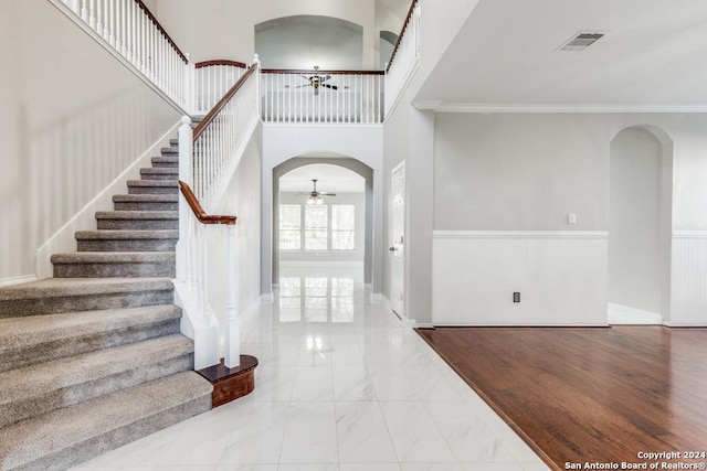 foyer with crown molding, a towering ceiling, and light hardwood / wood-style floors