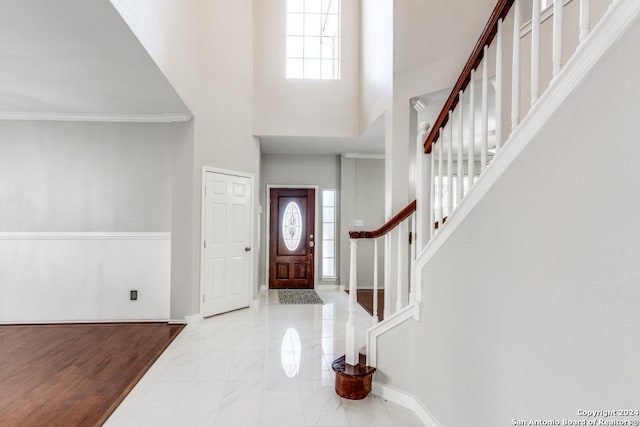 foyer with a towering ceiling and crown molding