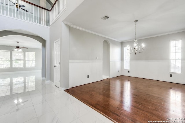 empty room featuring crown molding, light hardwood / wood-style floors, and ceiling fan with notable chandelier