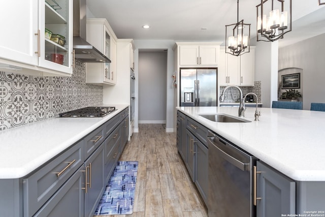 795 Maximino Ridge Rd, Bulverde, TX 78163 - kitchen with wall chimney range hood, stainless steel appliances, white cabinets, a chandelier, and light countertops