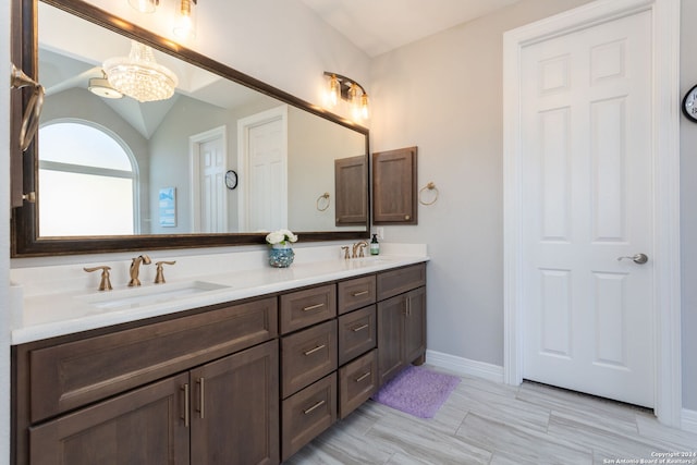 bathroom with vanity, vaulted ceiling, and an inviting chandelier