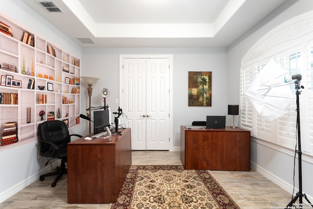 office space with a raised ceiling and light hardwood / wood-style flooring