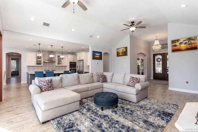 living room with french doors, sink, light hardwood / wood-style flooring, high vaulted ceiling, and ceiling fan with notable chandelier