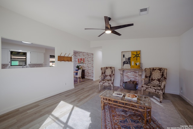 living room featuring a fireplace, light wood-type flooring, and ceiling fan