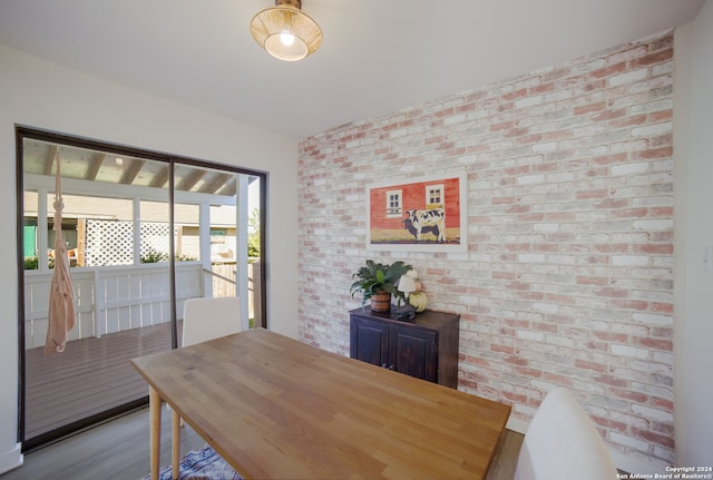 dining room featuring brick wall and light hardwood / wood-style flooring