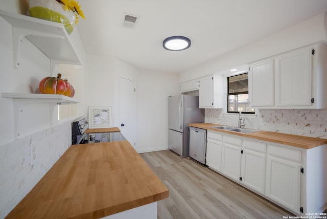 kitchen featuring sink, wood counters, light hardwood / wood-style floors, white cabinets, and appliances with stainless steel finishes