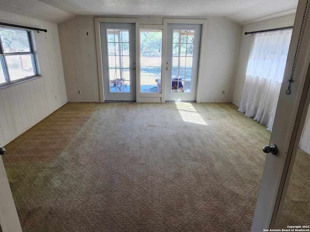 carpeted spare room featuring french doors and lofted ceiling