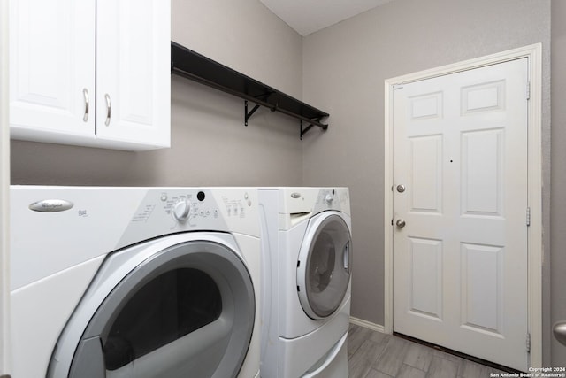 clothes washing area featuring washer and dryer, light hardwood / wood-style flooring, and cabinets