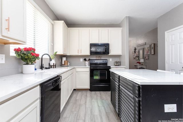 kitchen with light stone counters, a kitchen island, sink, black appliances, and white cabinetry