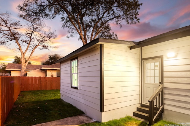 property exterior at dusk featuring a yard