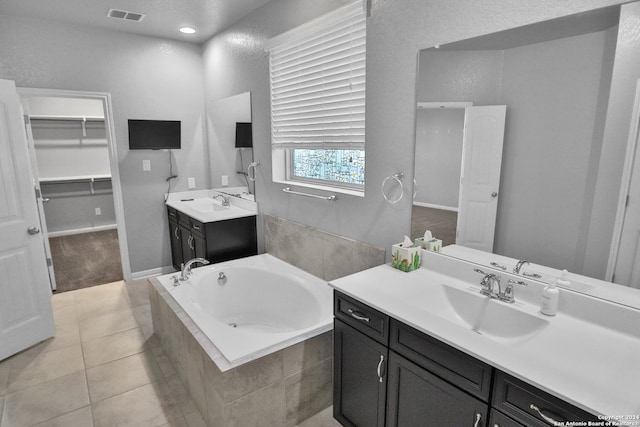 bathroom featuring tile patterned flooring, vanity, and a relaxing tiled tub