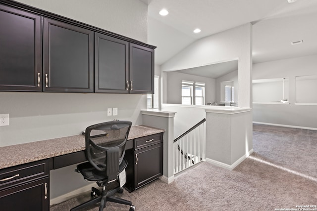 carpeted office space featuring built in desk and vaulted ceiling