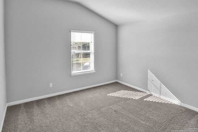 carpeted empty room featuring vaulted ceiling