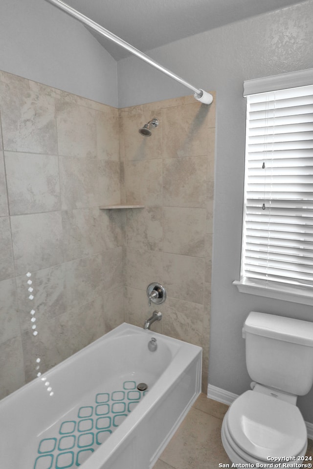 bathroom with tile patterned flooring, tiled shower / bath combo, and toilet