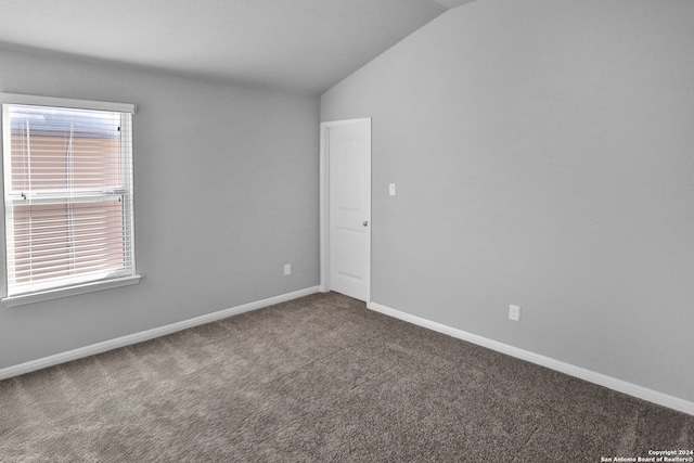 carpeted empty room featuring lofted ceiling