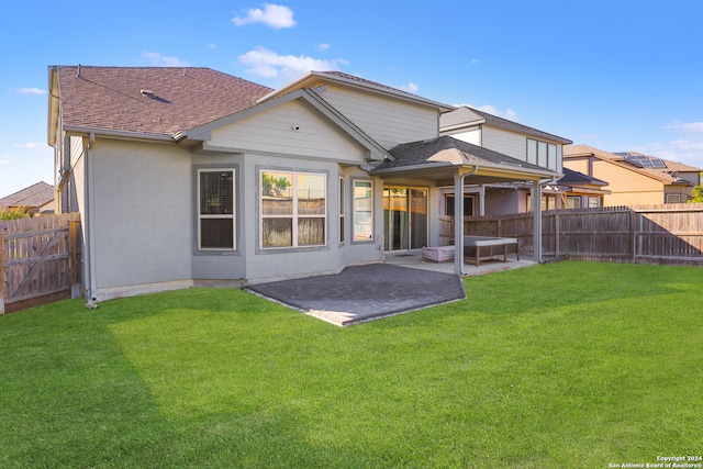 rear view of house featuring a lawn and a patio