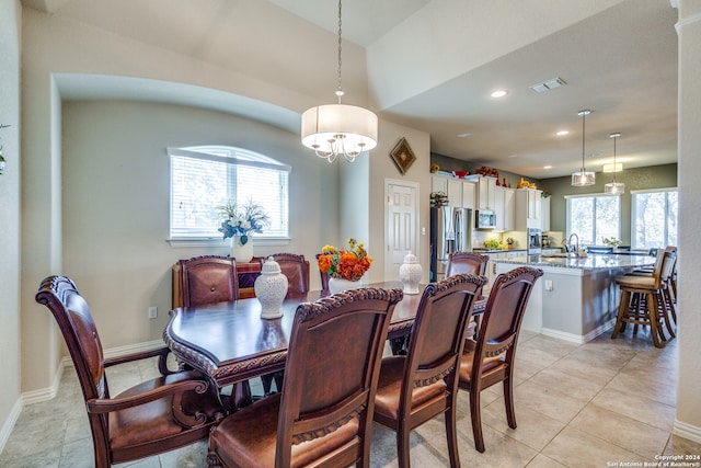 tiled dining area featuring plenty of natural light, a chandelier, and sink