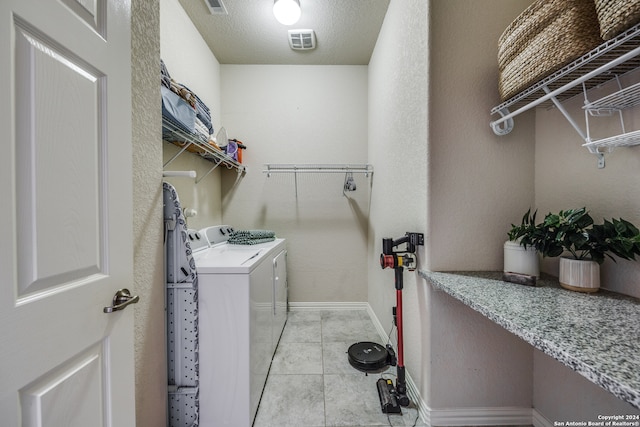 laundry area with light tile patterned floors, a textured ceiling, and separate washer and dryer