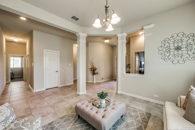 living room with a chandelier, light tile patterned floors, and decorative columns