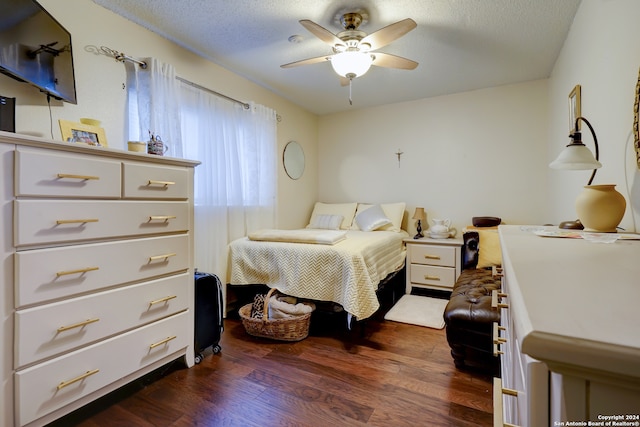 bedroom with a textured ceiling, ceiling fan, and dark wood-type flooring