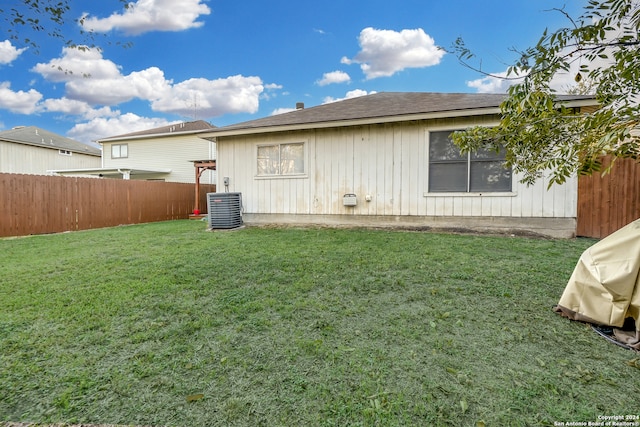 rear view of property with a lawn and central AC unit