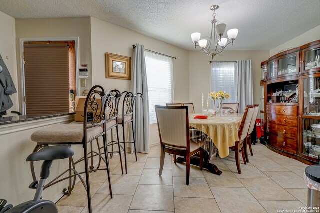 dining area with a notable chandelier, light tile patterned floors, and a textured ceiling