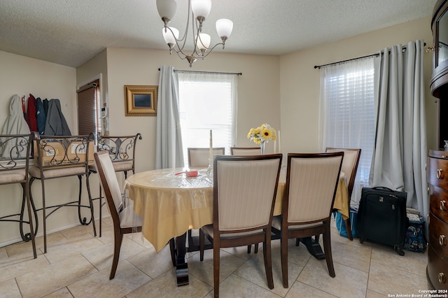 dining space with light tile patterned floors, a textured ceiling, and an inviting chandelier