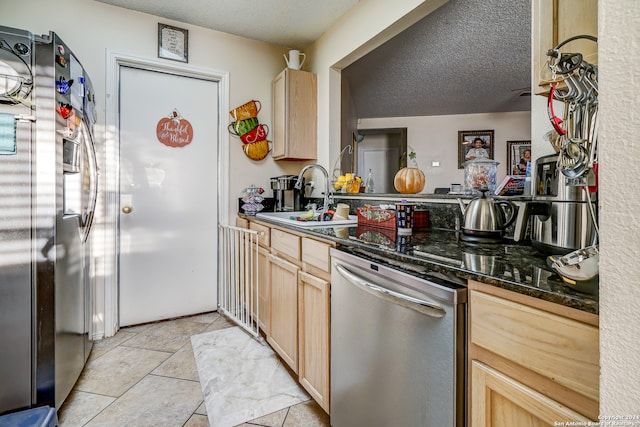 kitchen with sink, a textured ceiling, light brown cabinetry, light tile patterned flooring, and stainless steel appliances