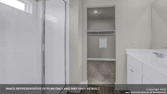 bathroom with hardwood / wood-style floors, vanity, and a shower with door