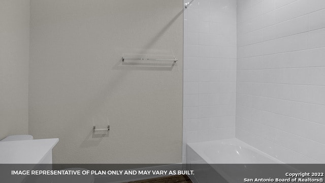 bathroom with tiled shower / bath combo and toilet